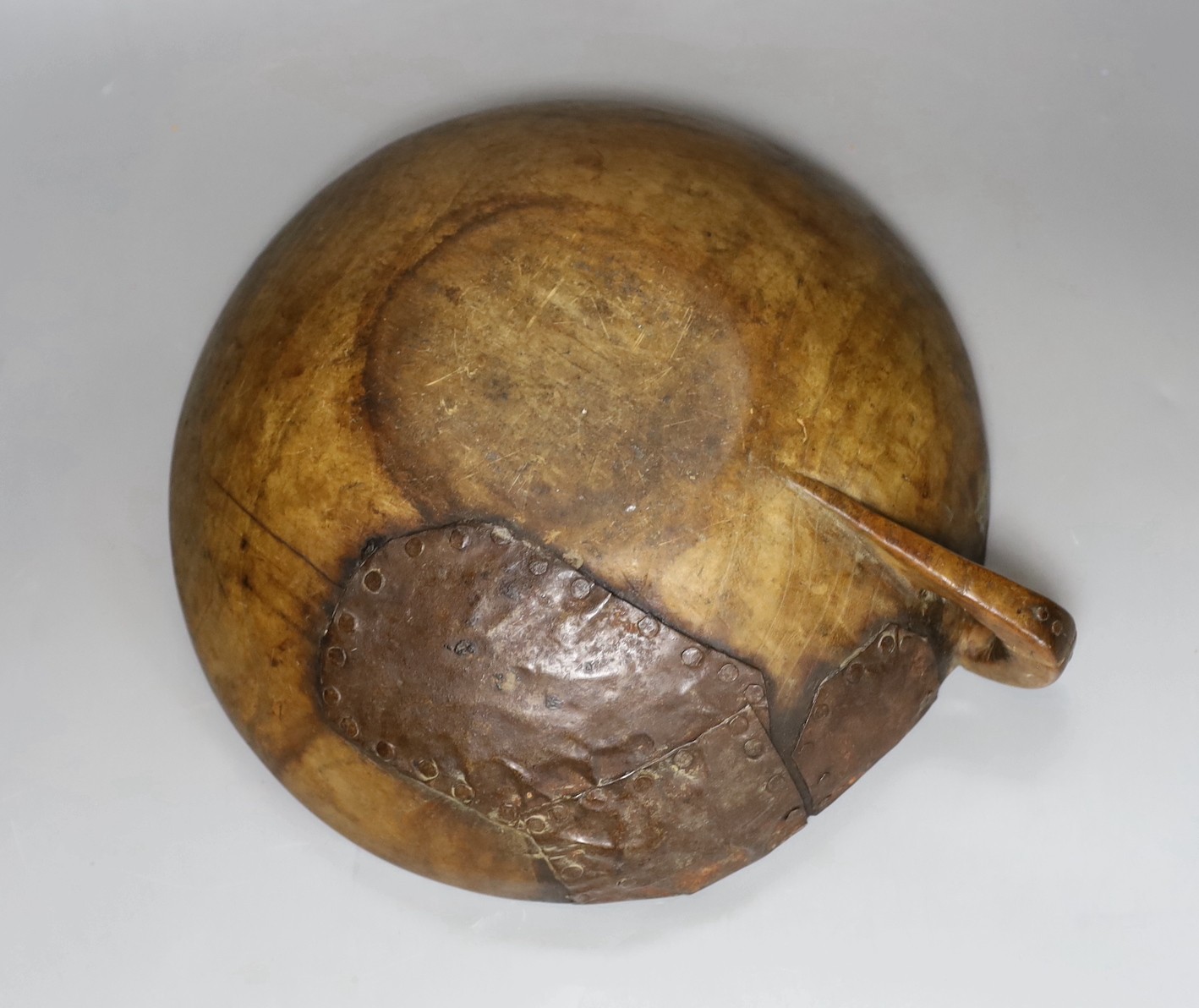 A carved elm mazer bowl, with old blacksmith repair, 31cm diameter